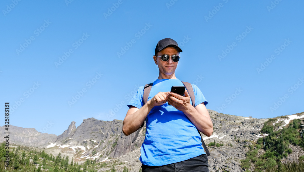 Traveling man using phone to take a photoes in mountain landscape