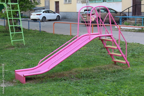 In the courtyard of the house there is a children's pink slide. photo