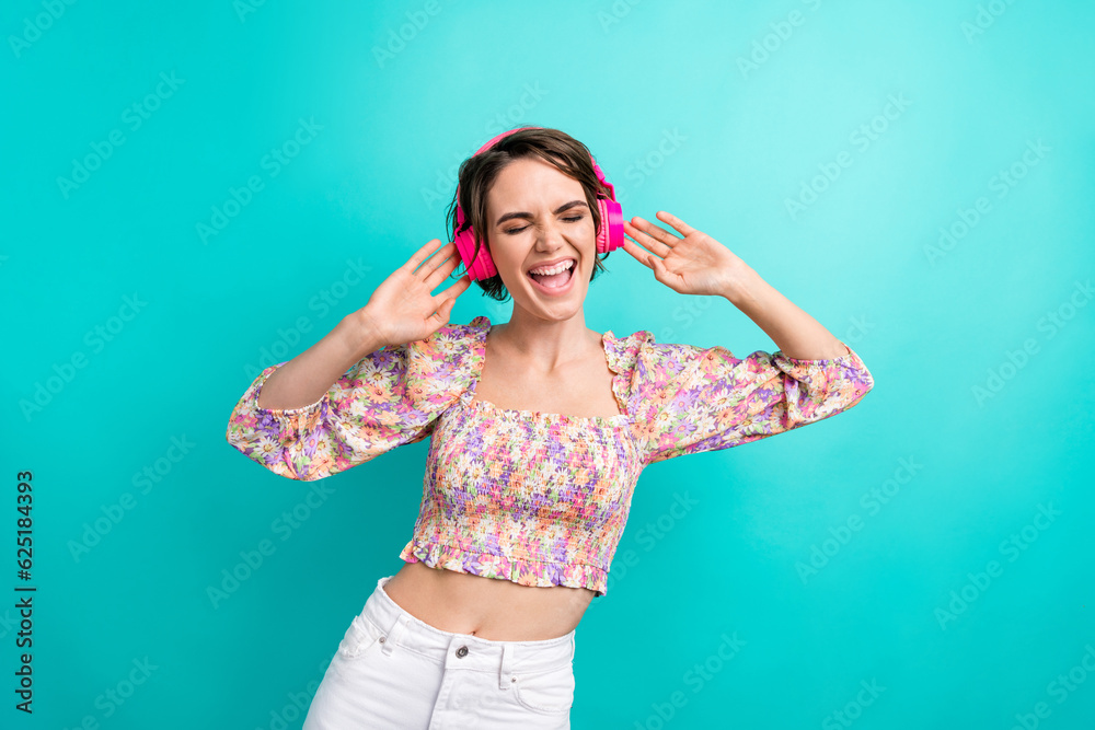 Photo of positive satisfied woman wear colorful dress eyes closed listen loud music in headphones isolated on turquoise color background