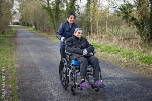 Elderly Indian woman in a wheelchair with daughter carer, UK
