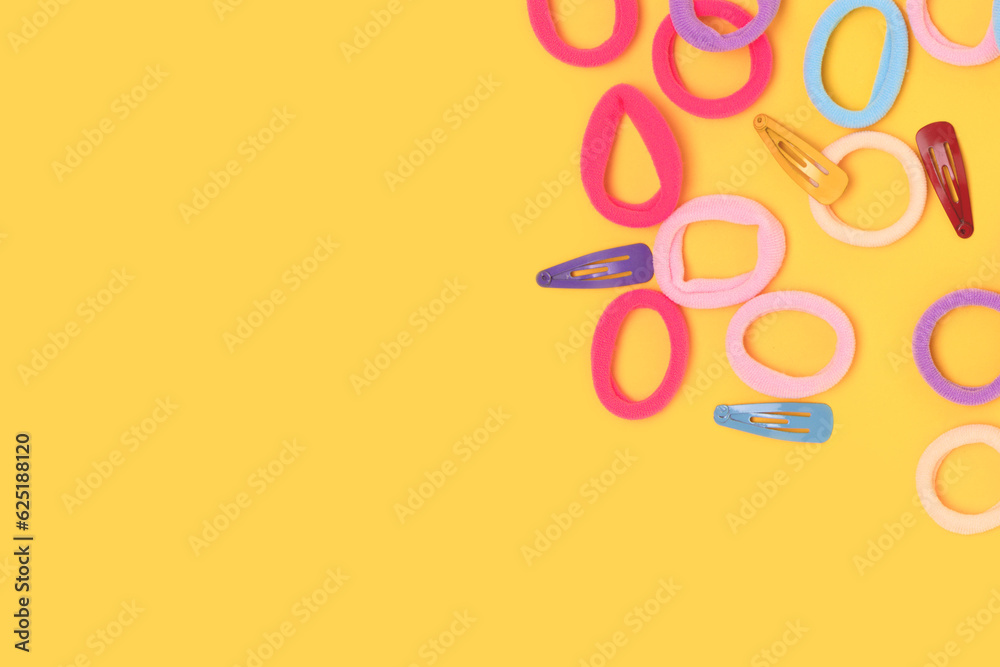 Naklejka premium Small multicolored hair scrunchies and clips on a yellow background. Place for text.