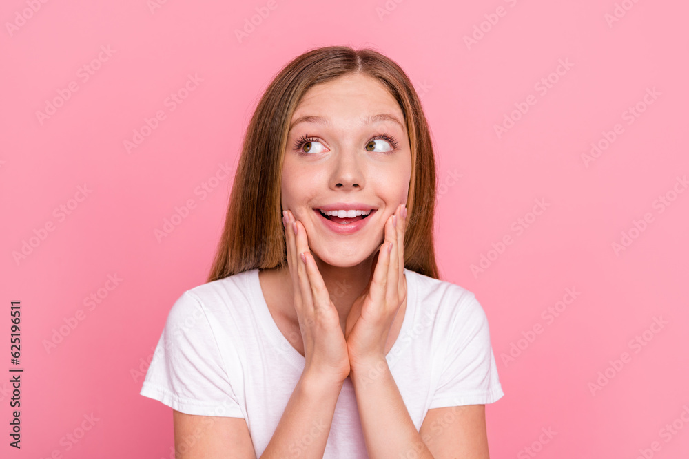 Portrait of charming cheerful minded girl hands touch cheeks look empty space ad isolated on pink color background Portrait of charming cheerful minded girl hands touch cheeks look empty space ad isolated on pink color background