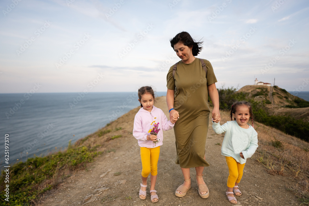 Mother and two daughters walking on a path by the sea in the evening. Cape Emine, Black sea coast, Bulgaria. Mother and two daughters walking on a path by the sea in the evening. Cape Emine, Black sea coast, Bulgaria.