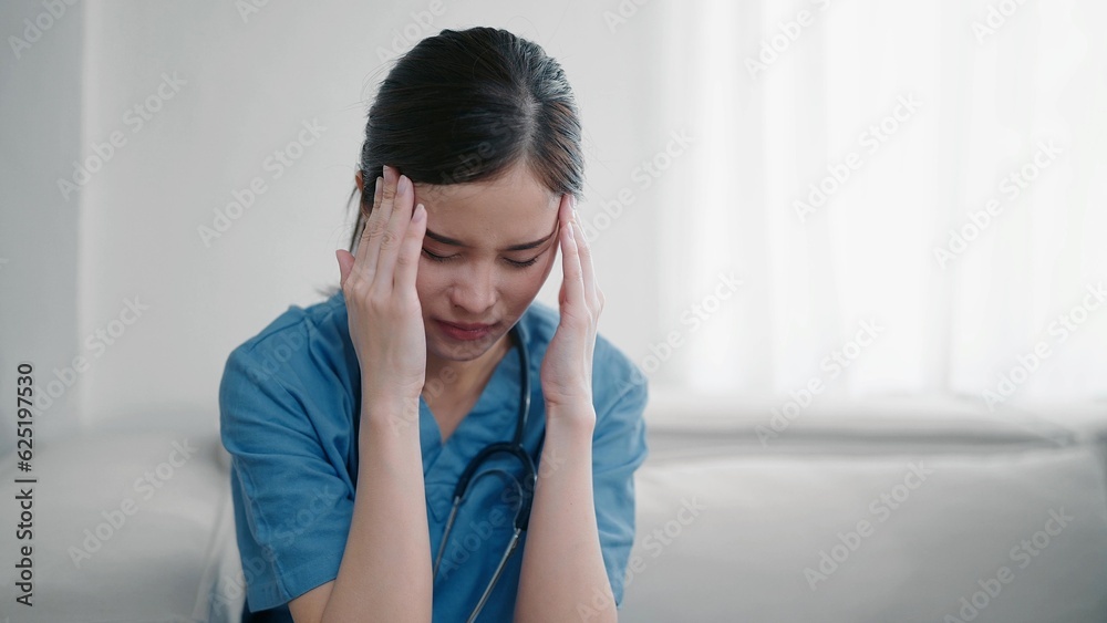 Tired depressed young asian woman nurse in uniform suffer from headache after hard working. Exhausted sad woman doctor feels burnout stress. Physician burnout Tired depressed young asian woman nurse in uniform suffer from headache after hard working. Exhausted sad woman doctor feels burnout stress. Physician burnout