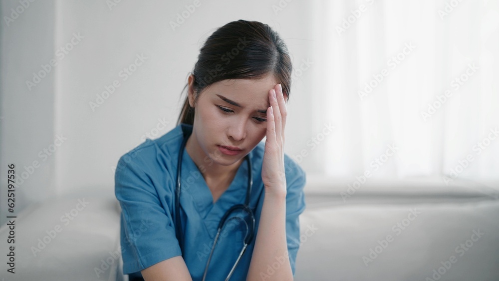 Tired depressed young asian woman nurse in uniform suffer from headache after hard working. Exhausted sad woman doctor feels burnout stress. Physician burnout Tired depressed young asian woman nurse in uniform suffer from headache after hard working. Exhausted sad woman doctor feels burnout stress. Physician burnout