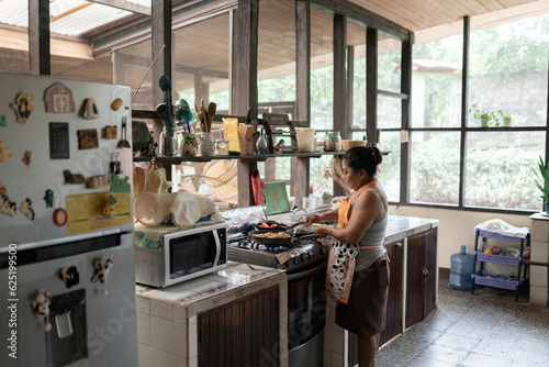 An adult Hispanic woman is cooking food in a big kitchen
