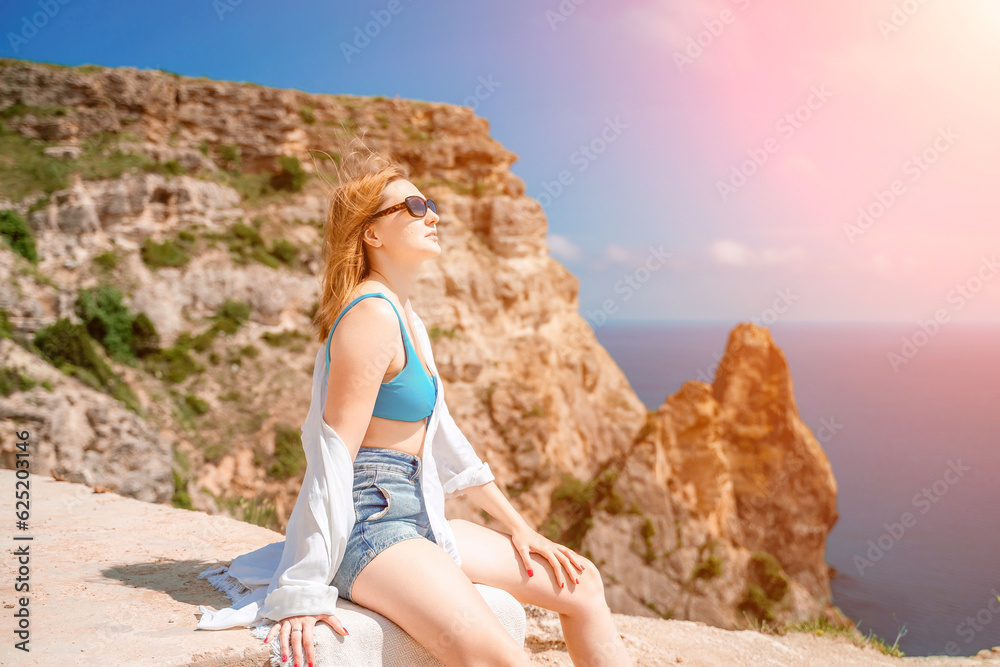 Woman travel summer sea. Portrait of a happy woman on a background of rocks and the sea. Side view of a woman in a white shirt and swimsuit. Freedom and happiness