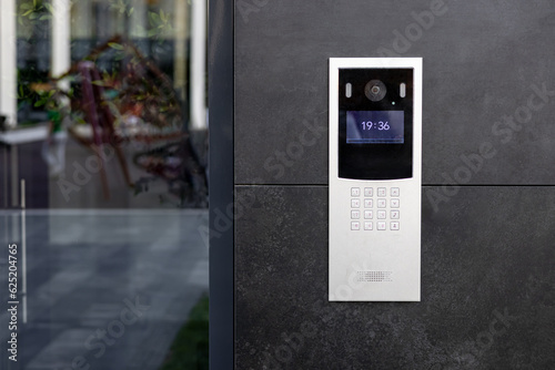 Entrance doorbell in a multi-apartment building, with a video surveillance camera, on a dark wall. photo