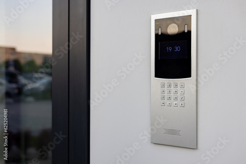 Doorbell with video camera and microphone, on the white wall of an apartment building, doorbell camera. photo