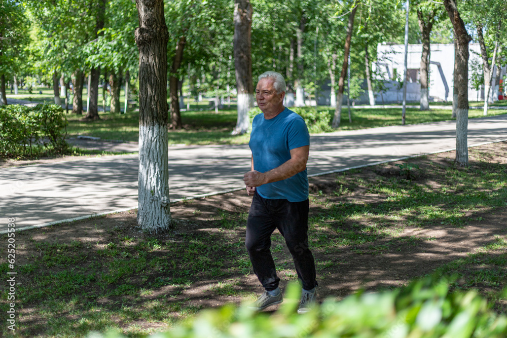 gray-haired man 50 years old jogging in the park in summer gray-haired man 50 years old jogging in the park in summer