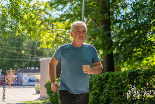 gray-haired man 50 years old jogging in the park in summer
