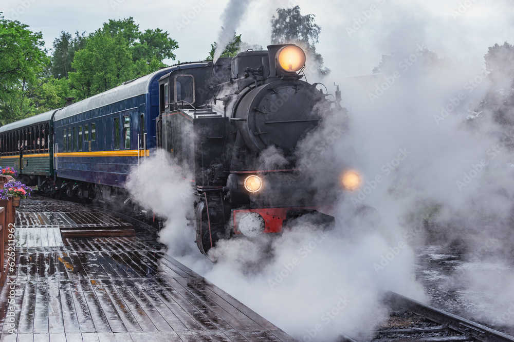 Fototapeta premium Retro steam train approaches to the platform.