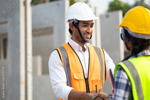 Asian indian man and woman engineering worker shaking hands on business cooperation agreement. Successful hand shaking after good deal Heavy Industry Manufacturing Factory. 