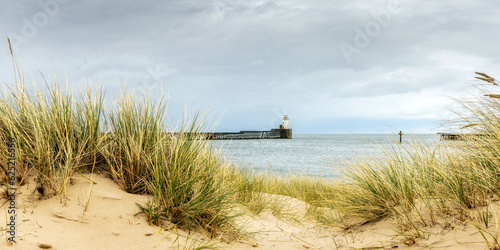 Fototapeta Naklejka Na Ścianę i Meble -  Blyth piers and lighthouse, seen from the dunes and marram grass beach.