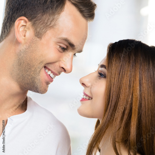 Profile side image of smiling happy amazed couple at home. Face portrait of standing close and looking at each other man and woman in love concept. Square picture.