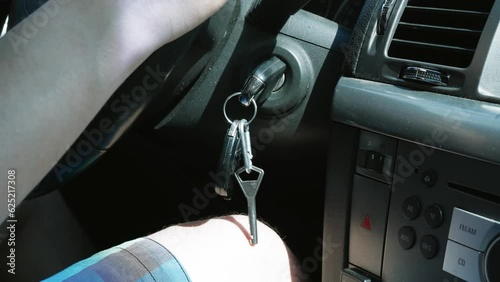 Keys in the ignition. Close-up of a key in a car ignition. Man's hand hold the steering wheel while driving the car. photo