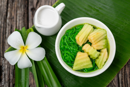 Top view of Lod Chong Thai dessert with coconut milk and pandan leaf on the wood background.