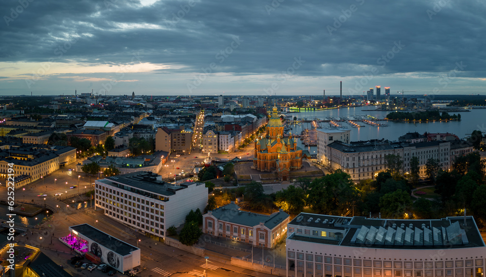Lights from buildings and historic church in Helsinki harbor at dawn