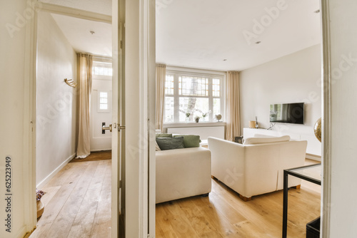 a living room with wood flooring and white sofas in the view from the doorway to the dining area