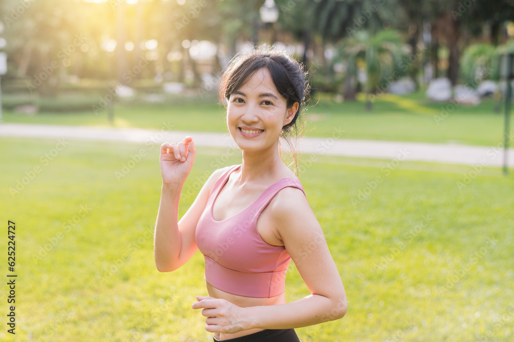 Capture the essence of wellness living as a happy, beautiful 30s Asian woman smiles and looks at the camera in a park at sunset. Capture the essence of wellness living as a happy, beautiful 30s Asian woman smiles and looks at the camera in a park at sunset.