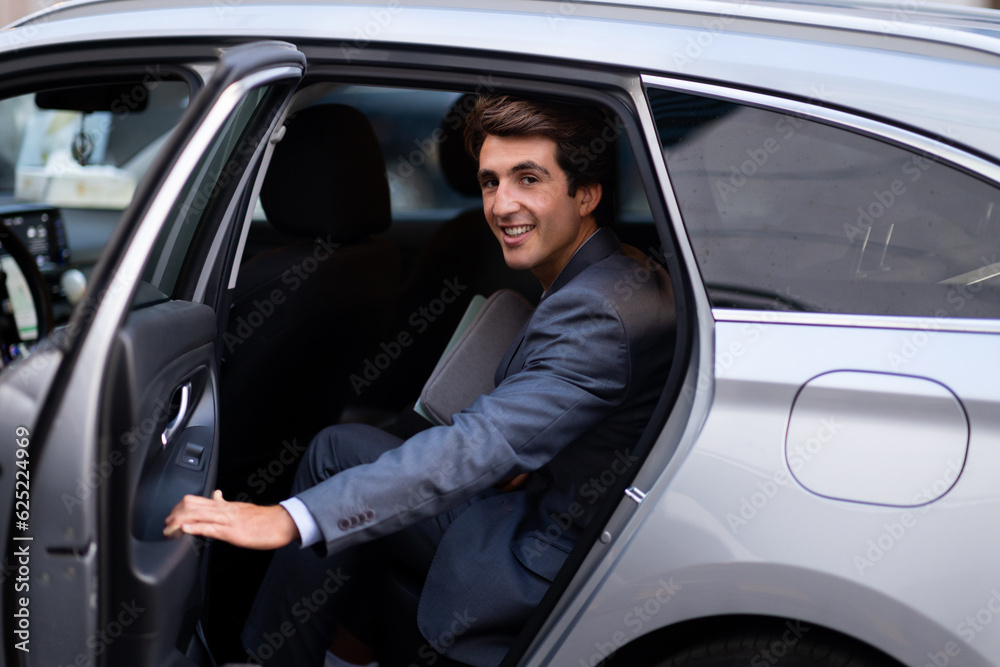 Cheerful young man entrepreneur getting into auto