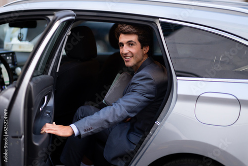Cheerful young man entrepreneur getting into auto © Prostock-studio