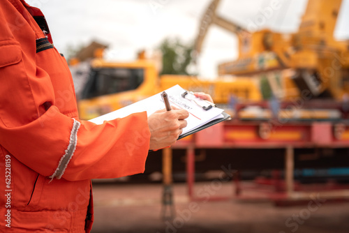 Tablou canvas Close-up at the operation supervisor is checking on heavy machine and equipment checklist form with crane truck as blurred background