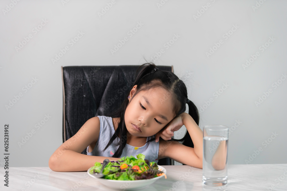 Little asian cute girl refuses to eat healthy vegetables.Nutrition & healthy eating habits for kids concept.Children do not like to eat vegetables. Little asian cute girl refuses to eat healthy vegetables.Nutrition & healthy eating habits for kids concept.Children do not like to eat vegetables.