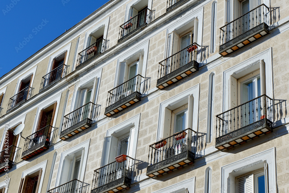 Facades of an old residential buildings with a beautiful exterior. Beige white building with stucco windows, wrought iron balconies. Historical vintage city architecture downtown Madrid, Spain Facades of an old residential buildings with a beautiful exterior. Beige white building with stucco windows, wrought iron balconies. Historical vintage city architecture downtown Madrid, Spain