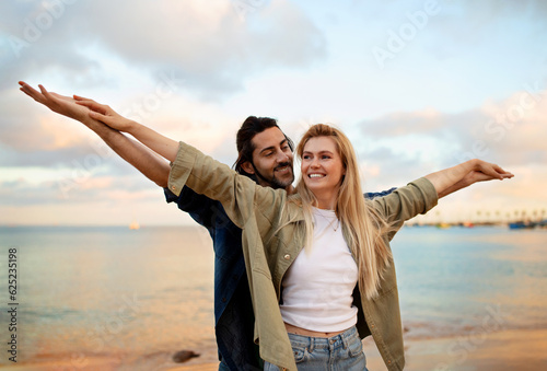 Let's fly. Joyful european couple having fun together at the beach