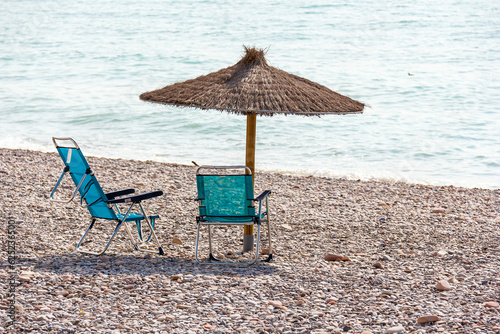 chairs under the thatched umbrella on the beach