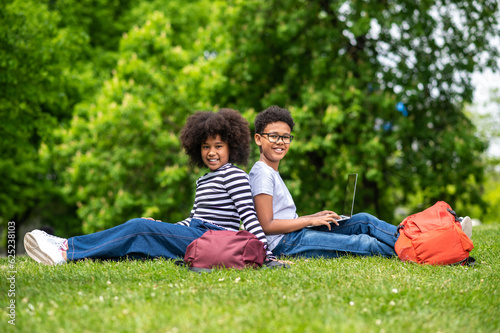 Two curly-haired teens sitting on the grass in the park and feeling good