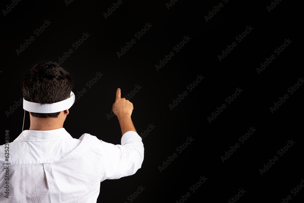 Back view of businessman wearing virtual reality googles pointing finger and touching invisible blank screen, free space Back view of businessman wearing virtual reality googles pointing finger and touching invisible blank screen, free space
