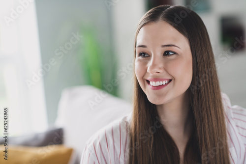 Photo of cute adorable young girl wear striped shirt smiling siting sofa indoors apartment room