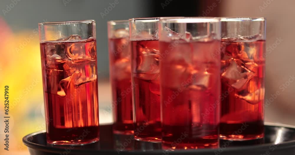 A tray with many glasses with drinks. Red drinks are delivered by a waiter. A tray with many glasses with drinks. Red drinks are delivered by a waiter.