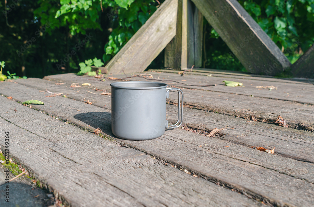 Gray metal cup in nature on wooden table Gray metal cup in nature on wooden table