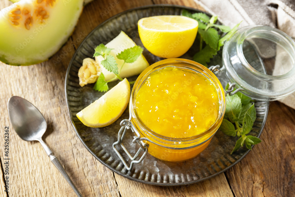 Homemade preserve. Sweet melon and citrus jam or jelly in small glass jar with fresh melon slices on wooden rustic table. Homemade preserve. Sweet melon and citrus jam or jelly in small glass jar with fresh melon slices on wooden rustic table.