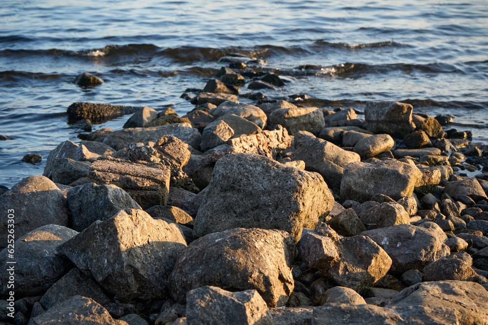 Tranquil shoreline with weathered rocks, a man finds solace while a bird surveys the serene waters, inviting contemplation of nature's beauty. Tranquil shoreline with weathered rocks, a man finds solace while a bird surveys the serene waters, inviting contemplation of nature's beauty.