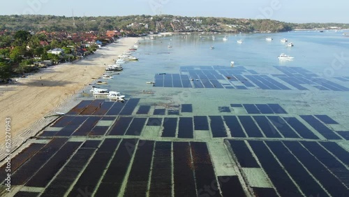 Aerial view of sea shore at Jungut Batu village in Nusa Lembongan with seaweed farm and tour boats anchored along the beach. Travel destination close to Bali, Indonesia. 4K drone footage video