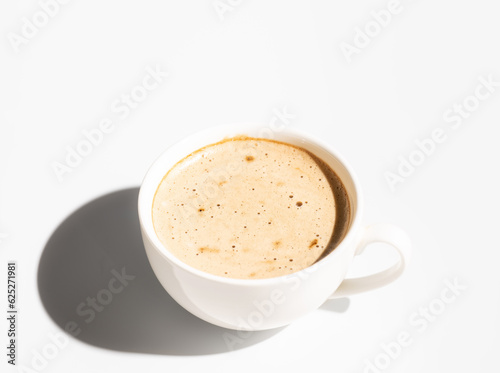 Side view of White Cup of cappuccino with creamy foam on white background. Copy space. Hard light