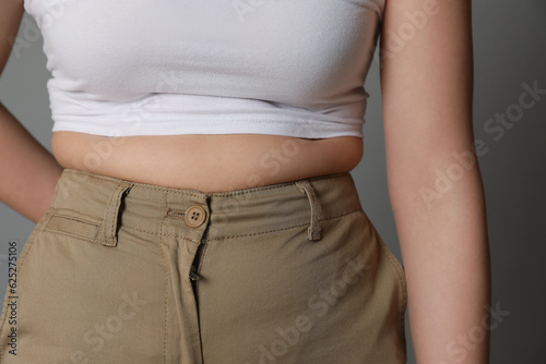 Overweight woman in tight pants on grey background, closeup © New Africa
