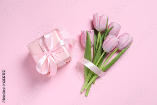 Fototapeta Naklejka Na Ścianę i Meble -  Beautiful gift box with bow and tulips on pink background, flat lay