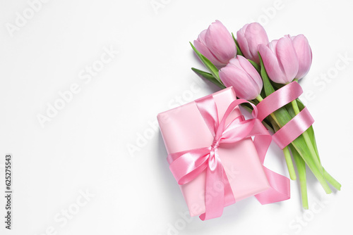 Beautiful gift box with pink bow and tulips on white background, flat lay. Space for text © New Africa