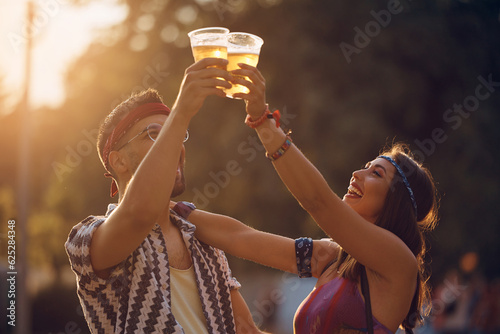 Happy couple toasting with beer during summer music festival.