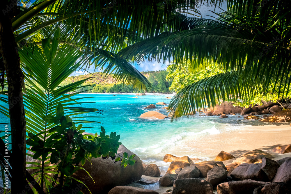 Fototapeta premium Summer landscape in the Seychelles. A beautiful bay with a boat surrounded by tropical defiles. Paradise tropical beach at sunset. Mae Island