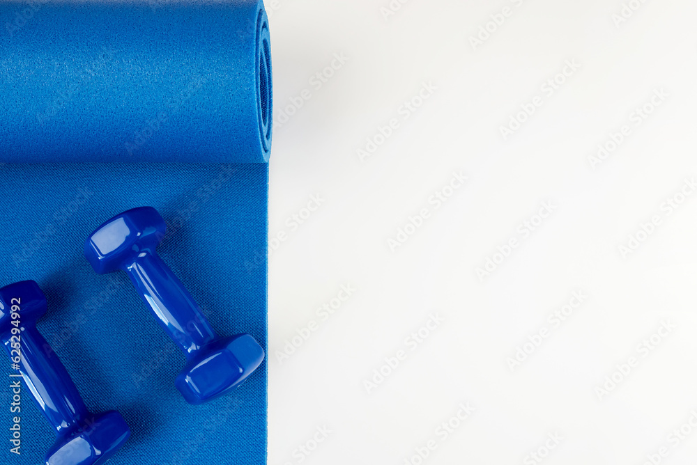 Fitness concept - blue yoga mat and dumbbells