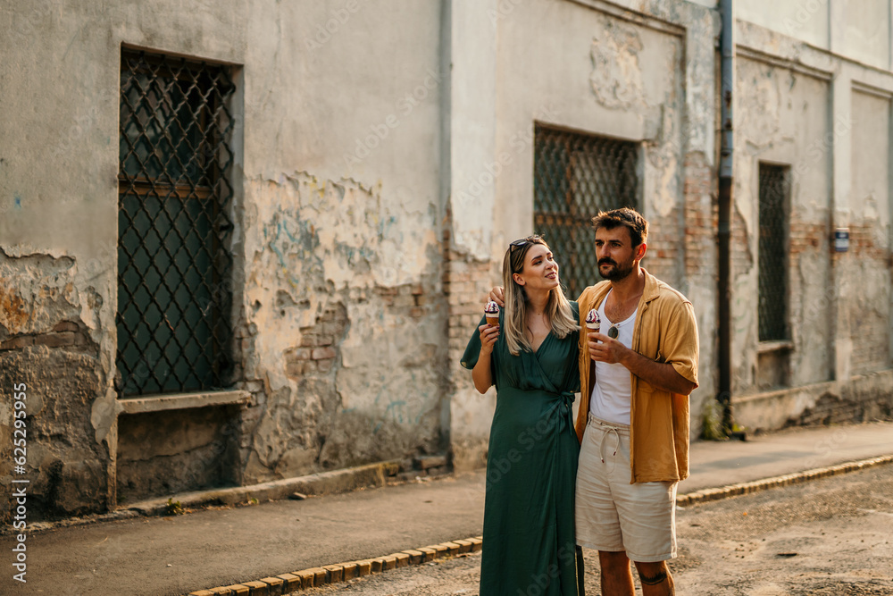 Tourists admire the architecture of a historic building while enjoying ice cream, blending the old and the new in their experience. Tourists admire the architecture of a historic building while enjoying ice cream, blending the old and the new in their experience.