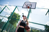 Young sports girl with a basketball on the basketball court outdoors,