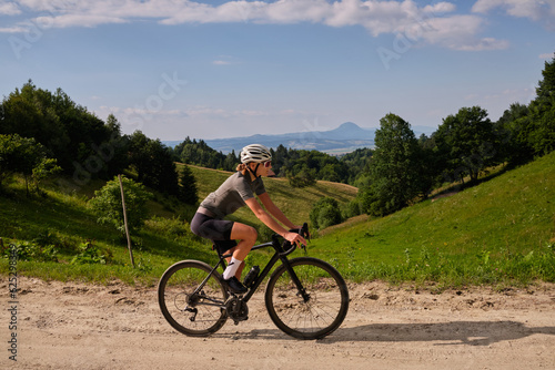 Tableau sur toile Female cyclist riding a gravel bike on a gravel road with a view of the mountains
