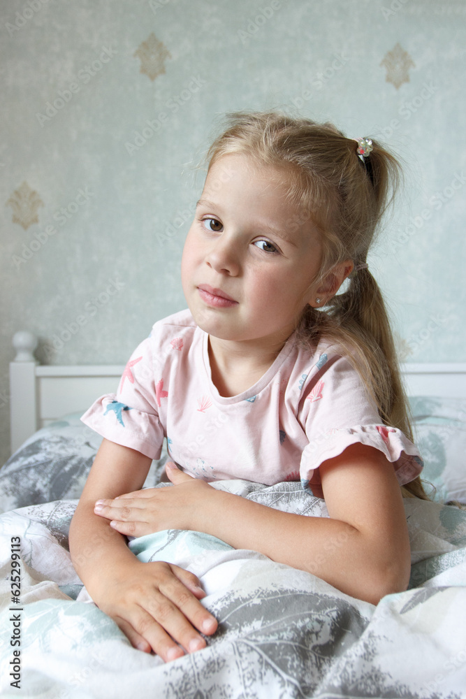 Cute little girl sitting on the bed and smiling. Concept of a leisure Cute little girl sitting on the bed and smiling. Concept of a leisure